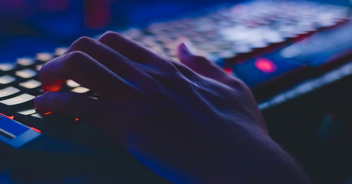 left hand typing on a keyboard in a dark room