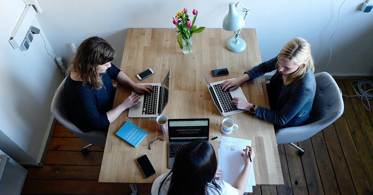 three coworkers collaborating together using unified communications on their apple laptop