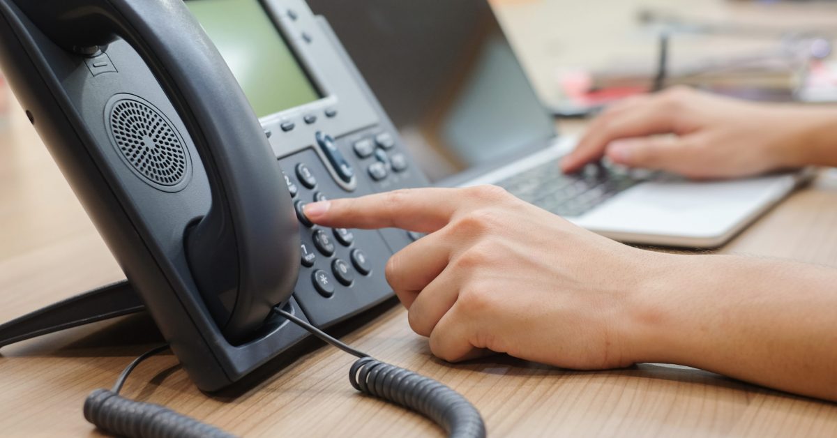 close up man hand pointing try to press button number on telephone office desk.multitasking employee concept