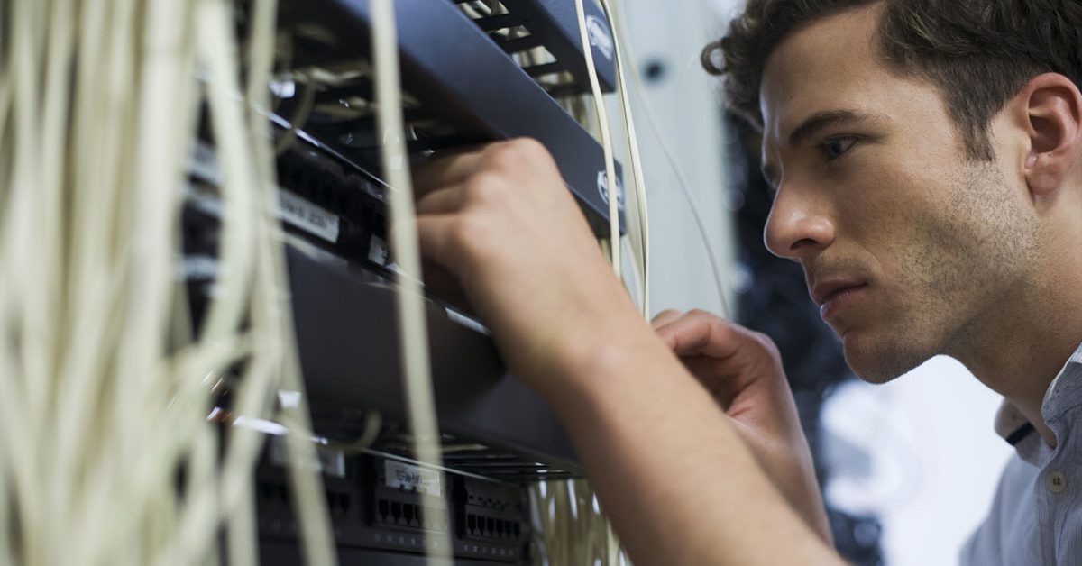 Computer technician performing maintenance on computer networking equipment